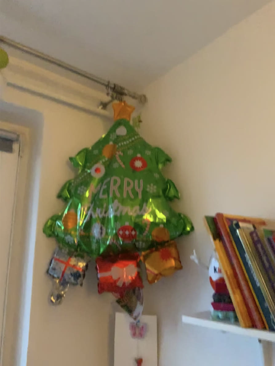 The wide camera framing a foil balloon against a wall, with a sliver of door frame and shelf at the edges.